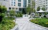 Curved walkways, plant beds and swimming pool surrounded by parasols and sun beds